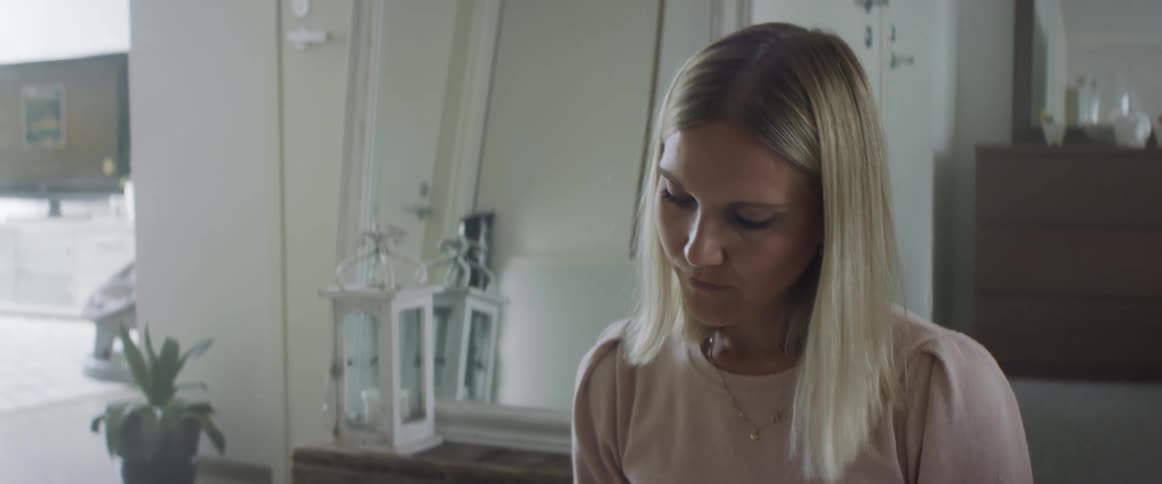 A woman at home looks at something and thinks