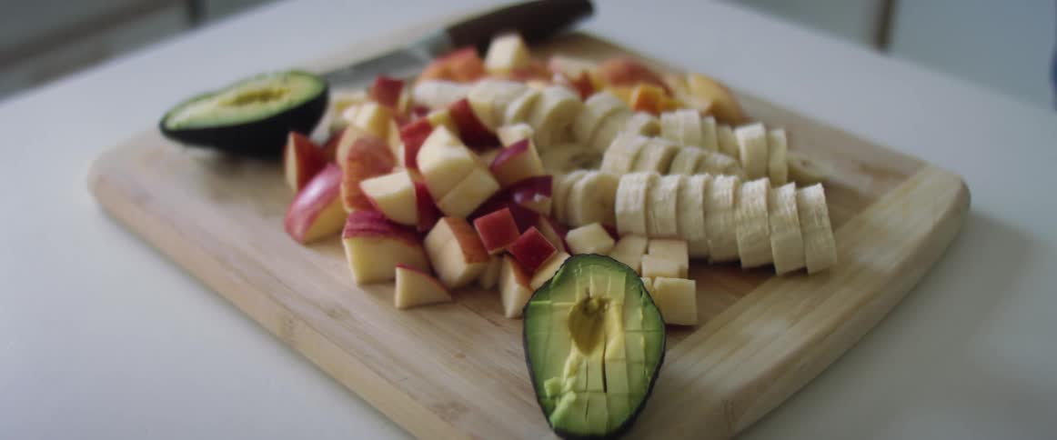Sliced mangoes bananas and apples on a cutting board