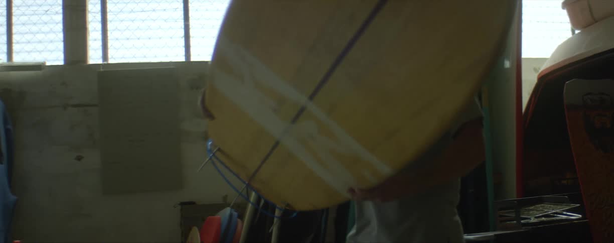 Man pulls surfboard from stand and puts it on a table