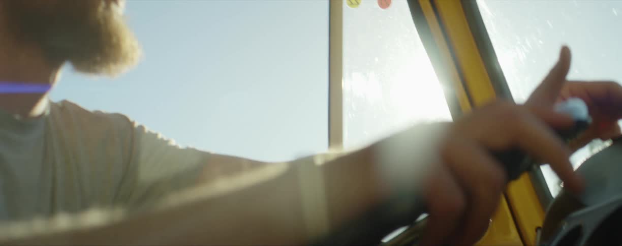 Young bearded man wearing sunglasses driving a car at day time