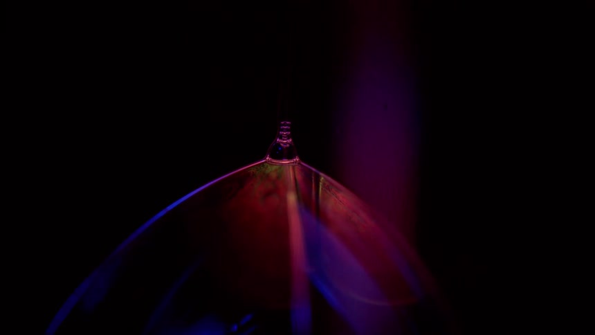 Blue light casts on a hanging object that is changing colors in a dark room