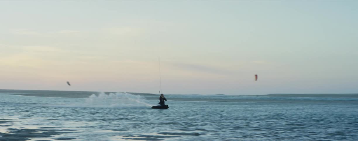 A person on a floating device in a lake with the sky and clouds in the background