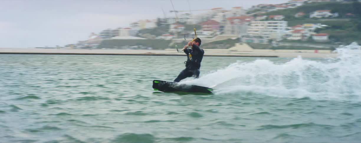 A man in the ocean holds on to a rope as he is pulled on a board