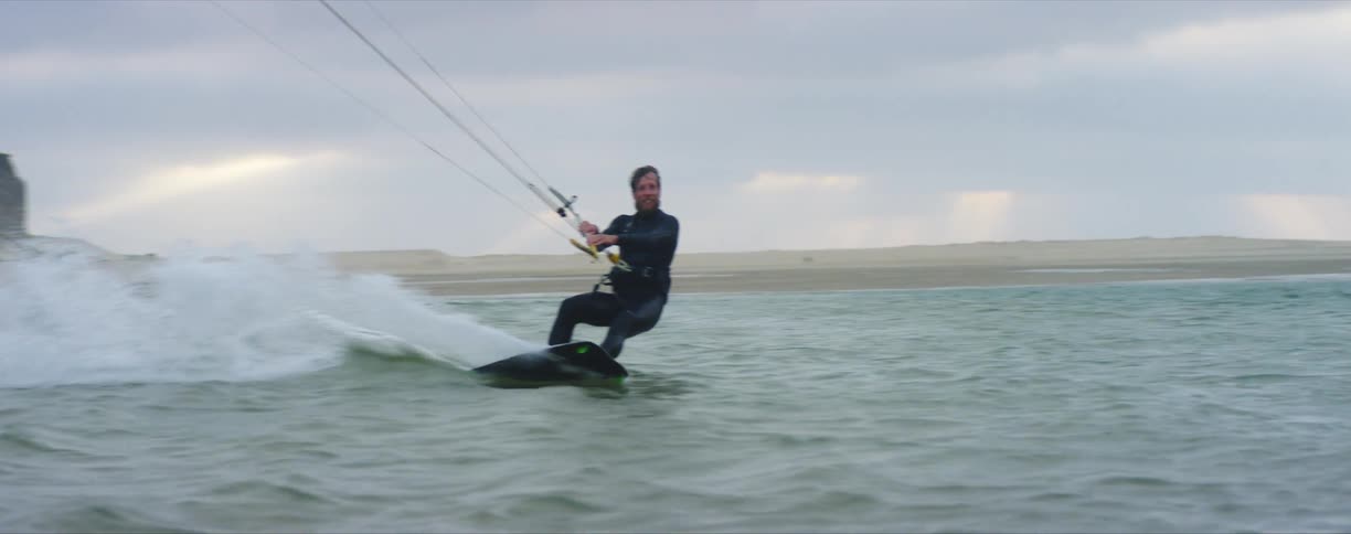 A man paraglides on the ocean wearing a wetsuit
