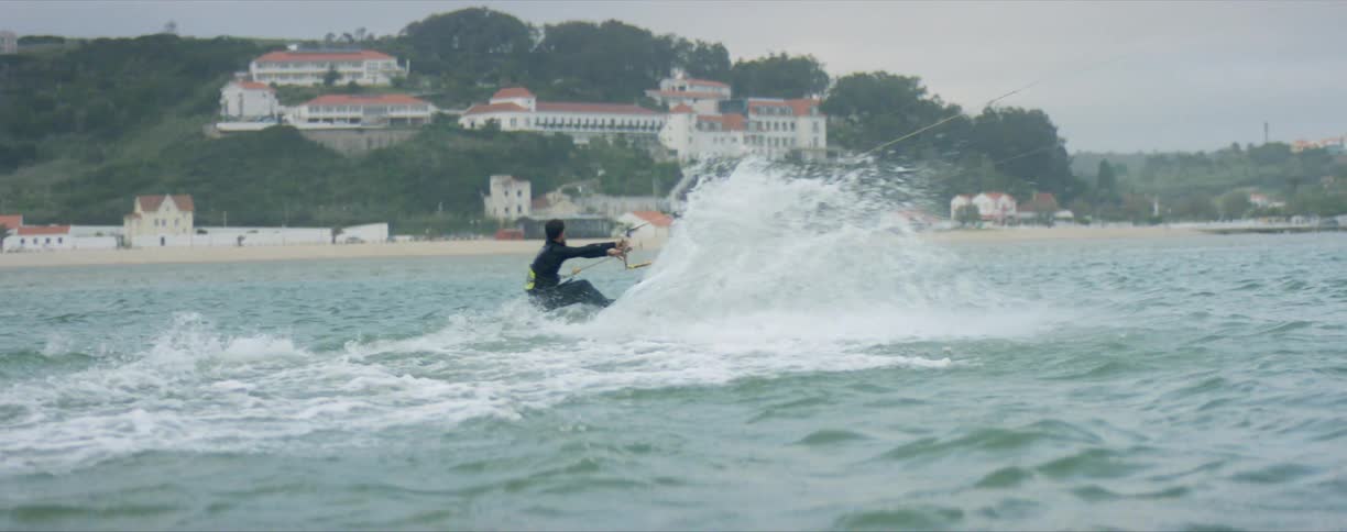 A man laughs as he is pulled on water skis through the ocean