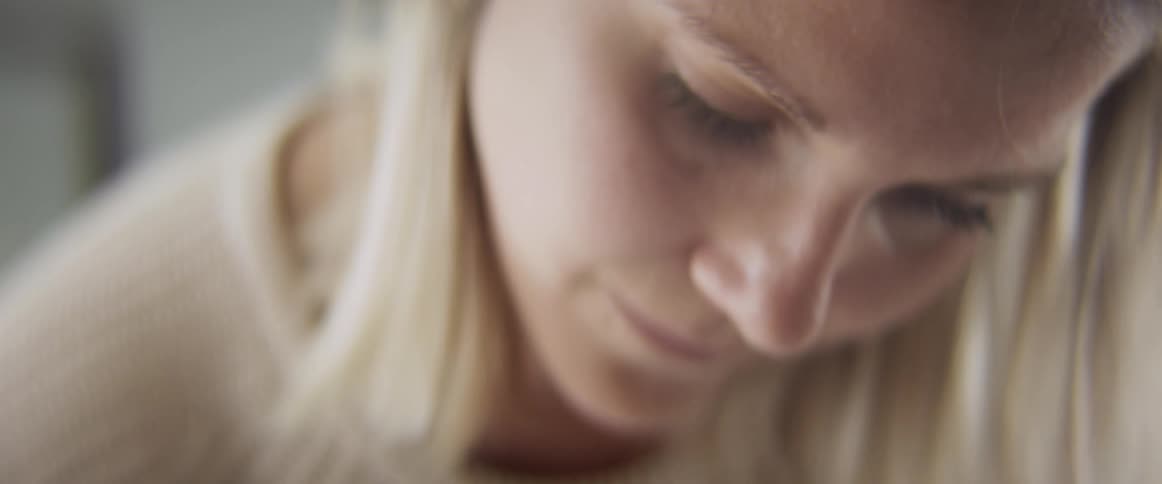 Blonde woman faces the camera without eye contact looking down