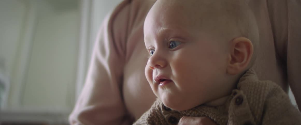 Mother holds her baby who watches a tablet attentively