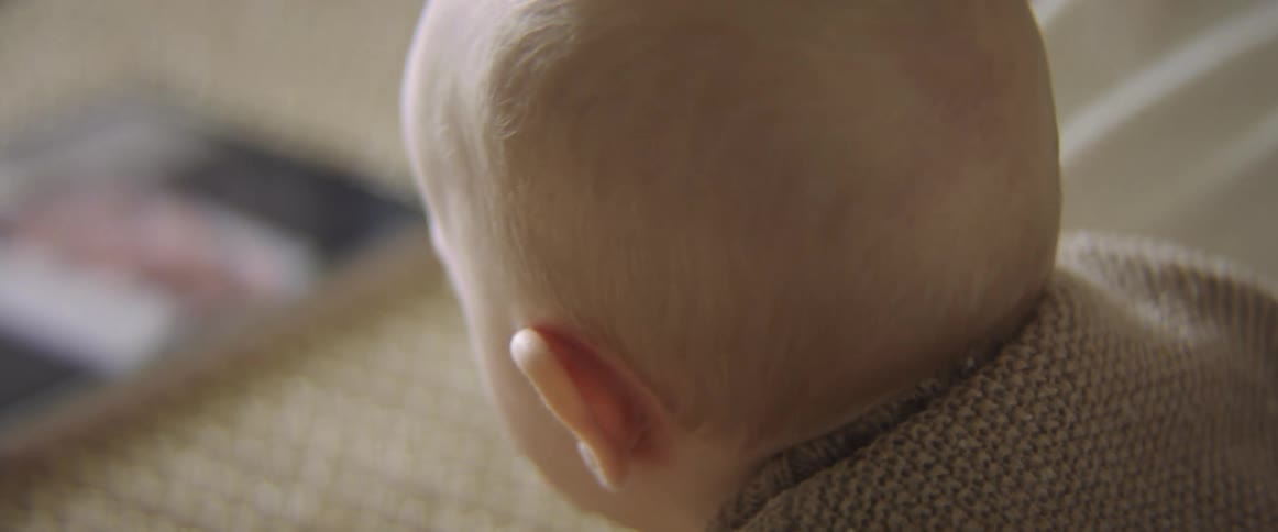 A baby crawls on the floor towards a tablet before the tablet is lifted by another person