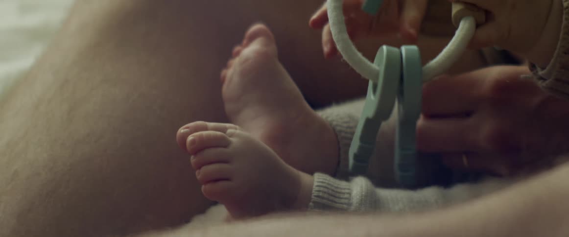 Man plays with child sitting near him and toy