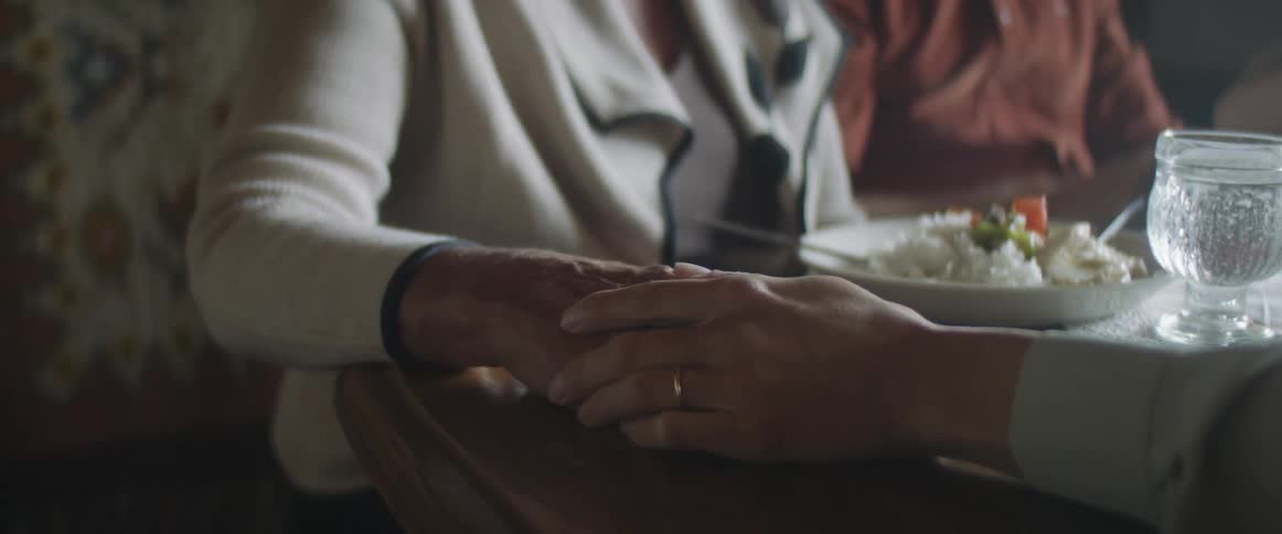 Two people holding hands on the table over a meal