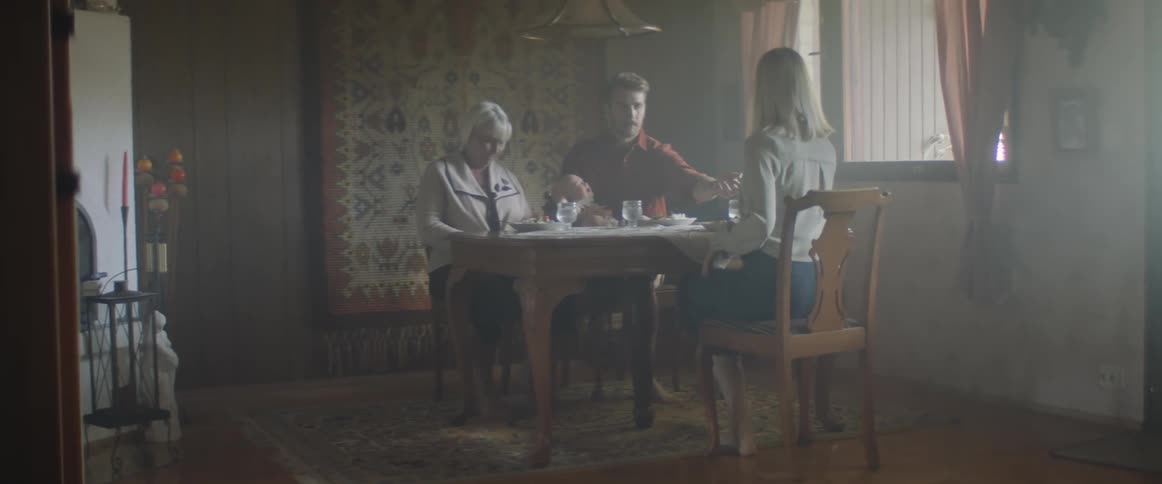 Family sit down at the table of a dimly lit dining room at home