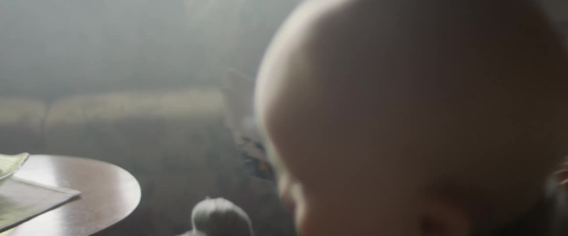 A adult holds a baby and attempts to prevent the baby from grabbing the photographs from out of their hands
