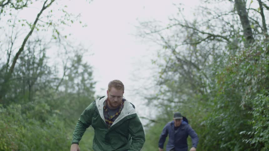 Two men skateboarding down a trail