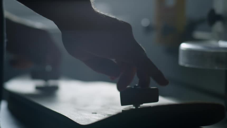 Man stands in shadowy room turning knobs