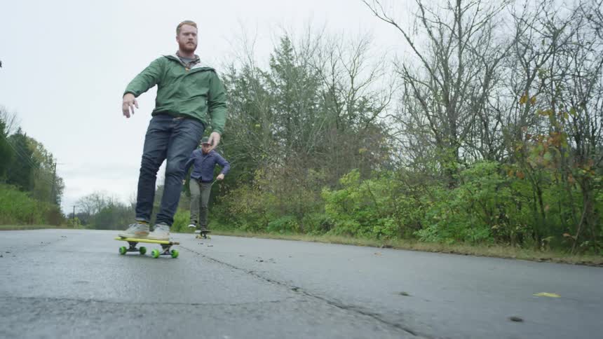 Two men skateboarding down a hill