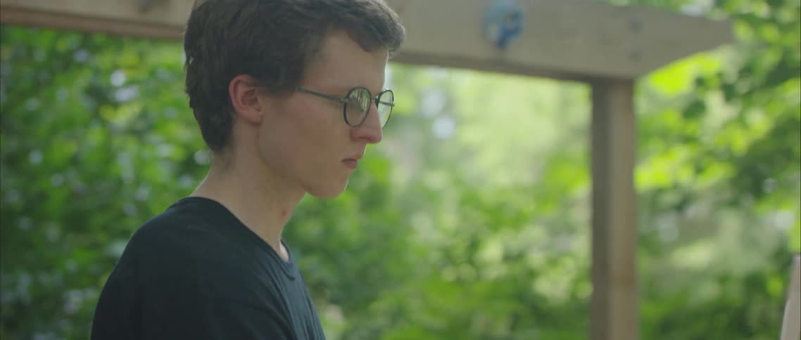 A teenage boy paints in a back yard