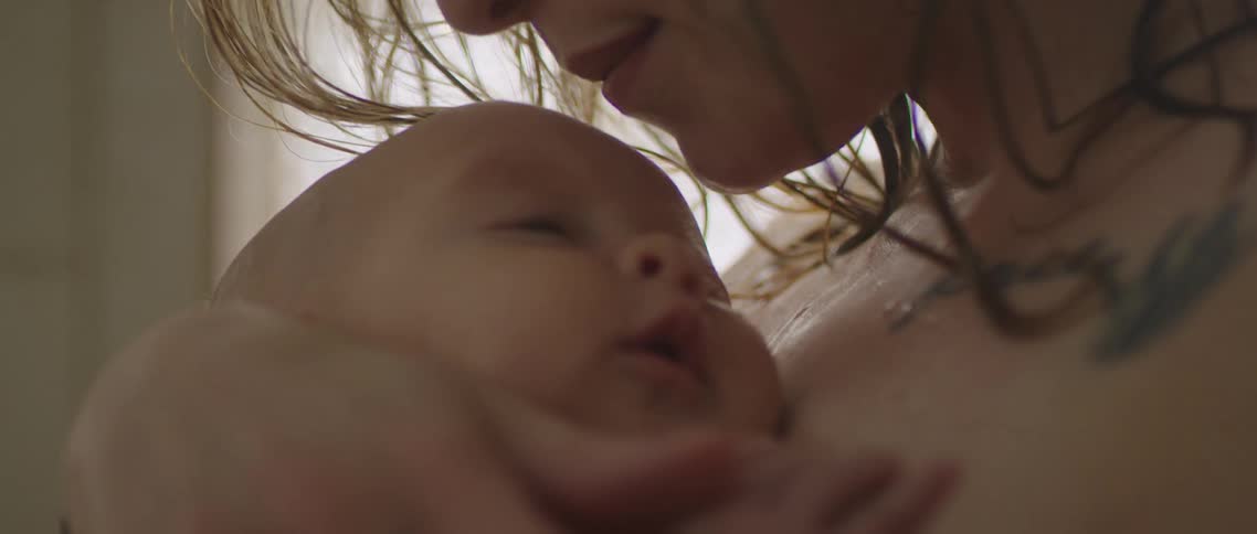 Mother kisses a baby forehead standing inside the shower in the bathroom at home