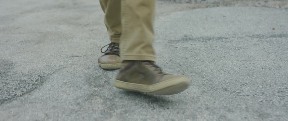 A person in brown shoes dancing while walking outside