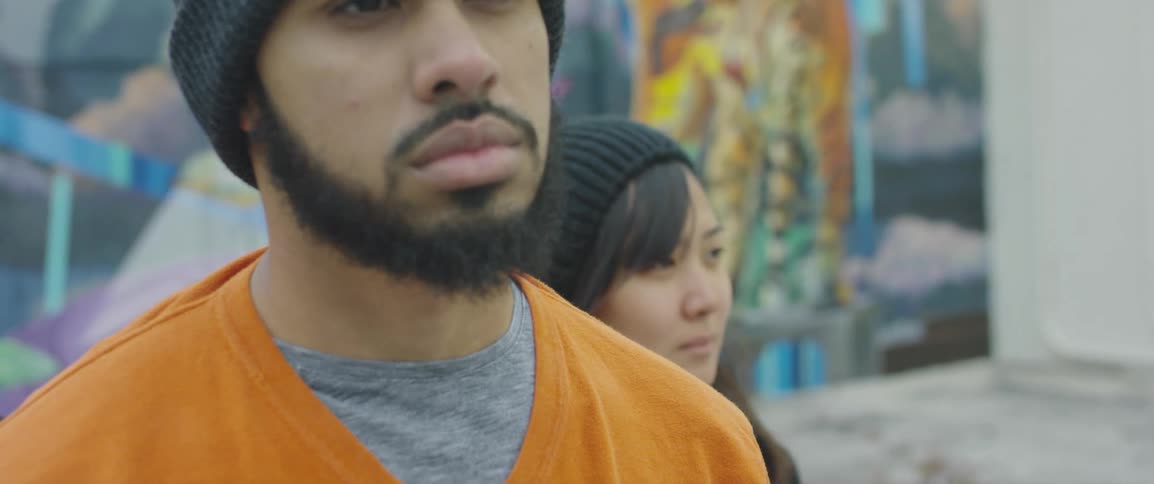 A young couple standing still looking away from a painted wall