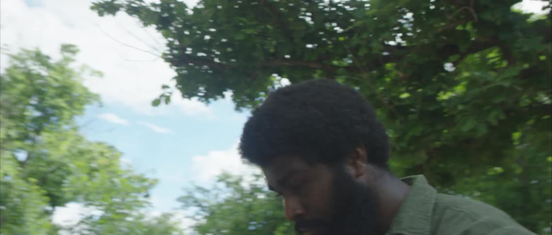 Man stands outside with houses in background dancing