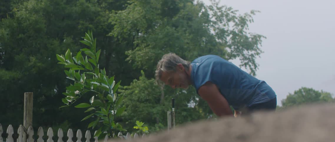 A man uses a shovel on his garden outside