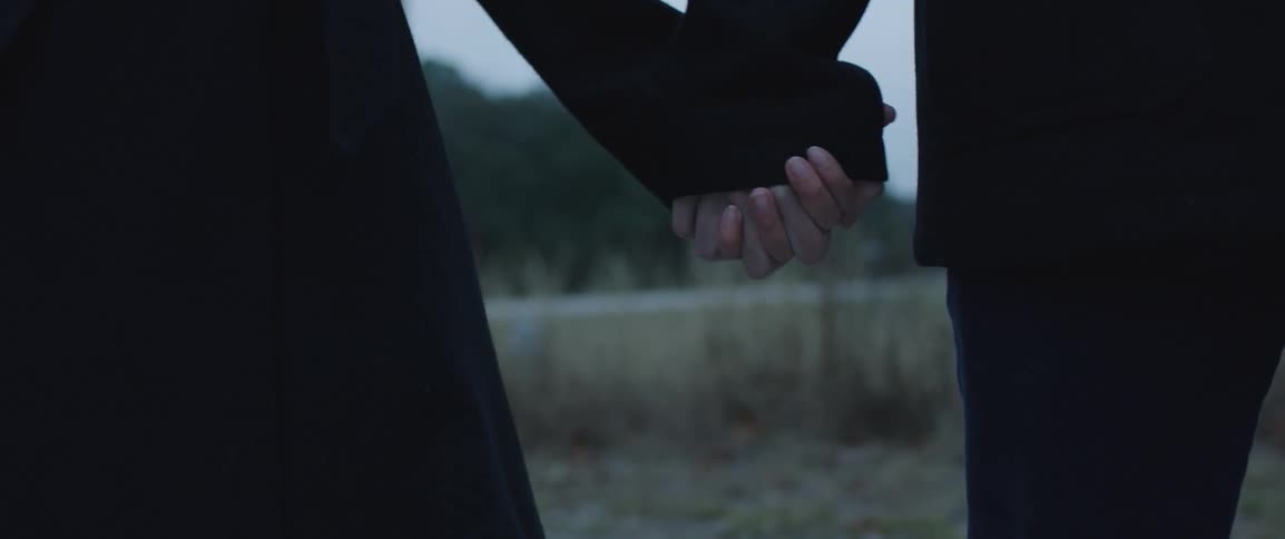 Young couple holding hands near a road in a rural area in a cold day