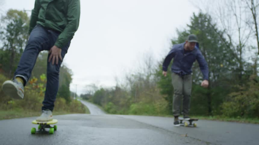 Two men skateboarding down a trail