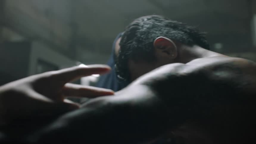 A boxer sits indoors as two men massage his arms