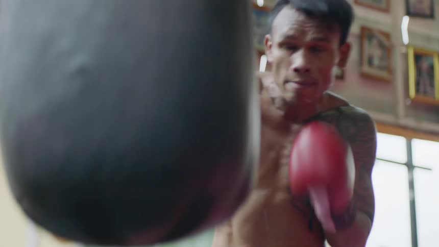 A man works out by boxing with a bag in a boxing ring