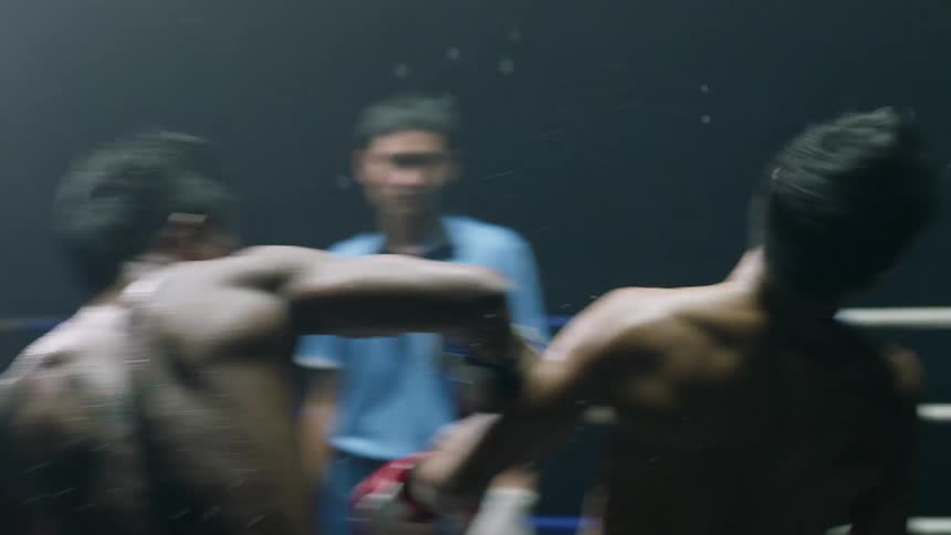 Two men are boxing in a ring while a referee watches as one is knocked out with a punch