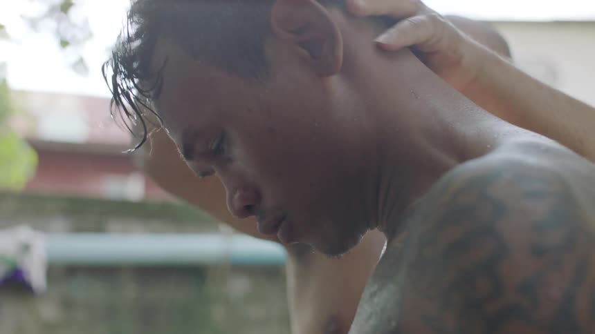 A man is loosening another mans muscles on his back and neck as they stand outside
