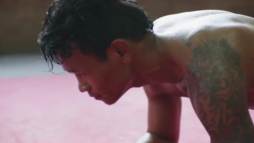 Sweat drips from a fighters forehead and hair as he does a plank while training