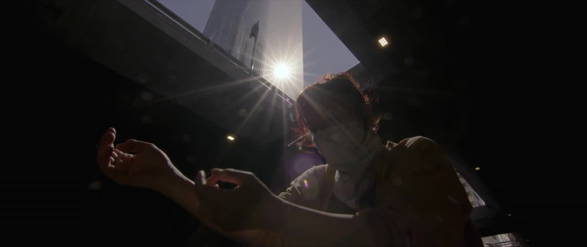 Young woman wearing a face mask performing a contemporary dance under a bridge near a skyscraper