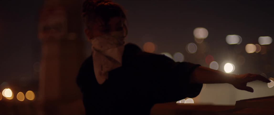 A woman performs a dance on a roof top at night
