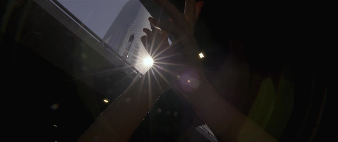 Dancer moves their hands in light coming through skylight from sun