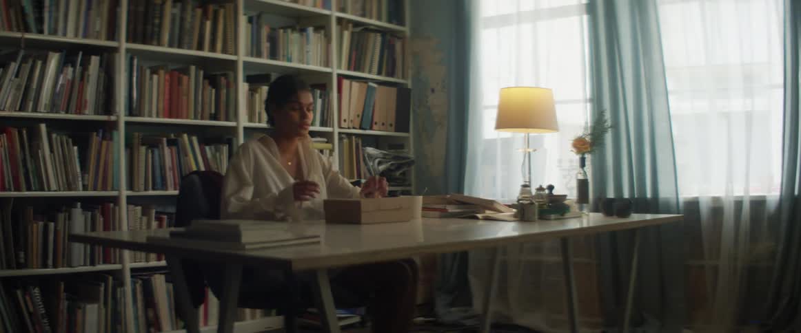 A woman is walking around a room that is filled with books