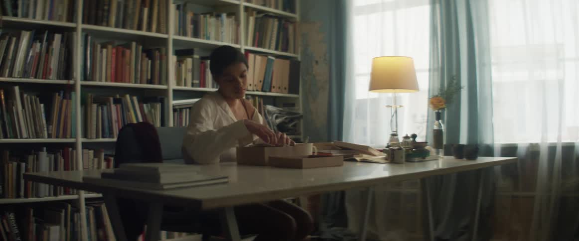 A young woman sits at home and goes through a box of photos