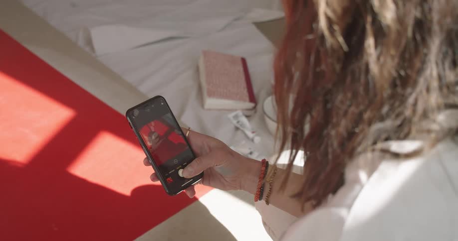 Person with messy hair looks at photos on a smart phone