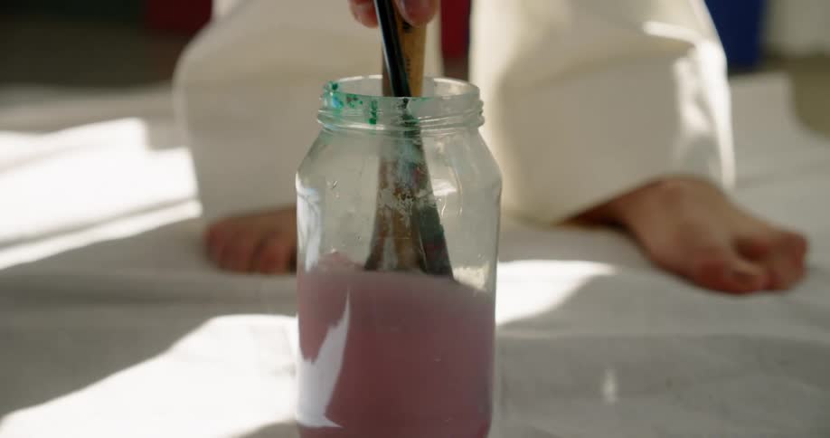 A person putting a paint brush in water