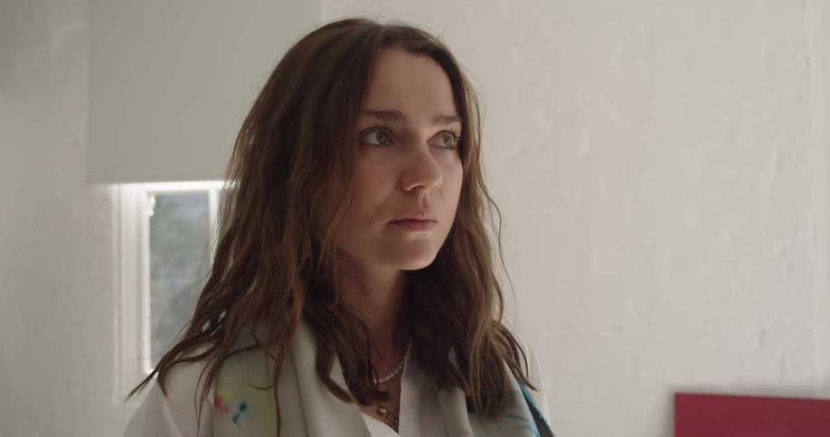 A woman stands in a room and looks at paintings
