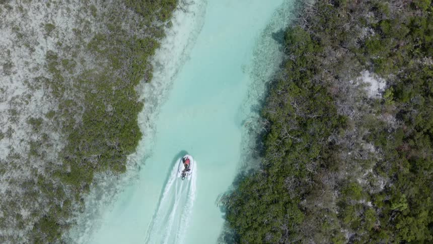 Aerial view of a boat traveling over the clear blue waters of a river