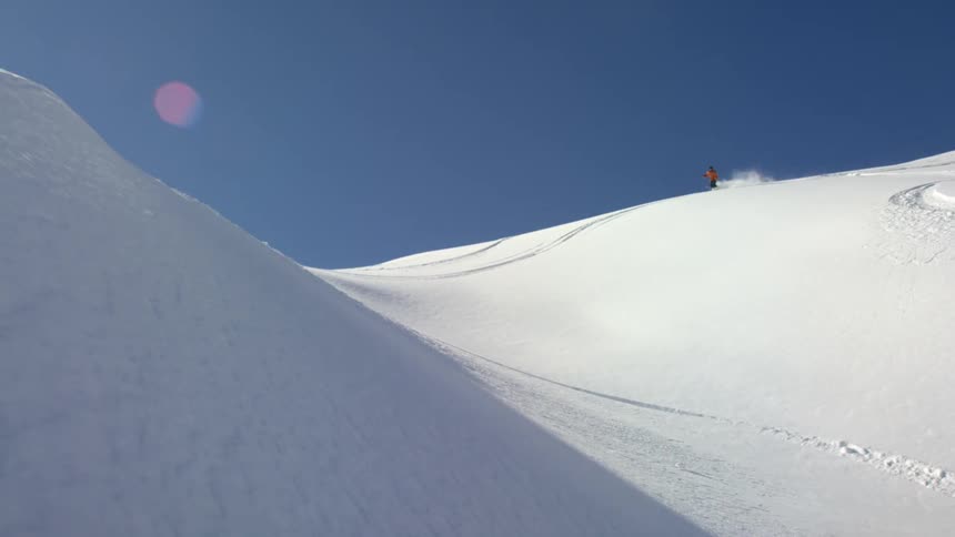 A person skis down a snowy slope of a mountain