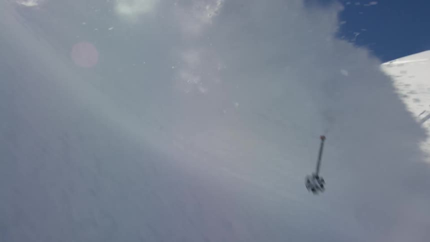 Snow sprays in to the air as a person skis down a mountain