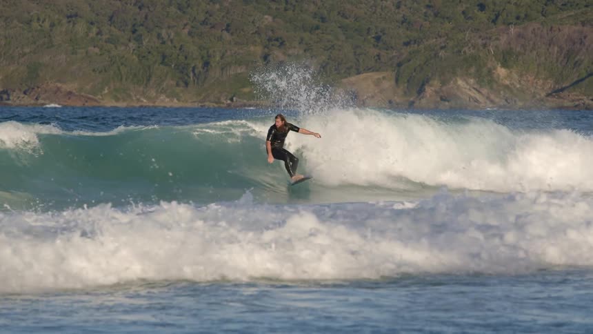 Male surfer rides a big wave and water splashes
