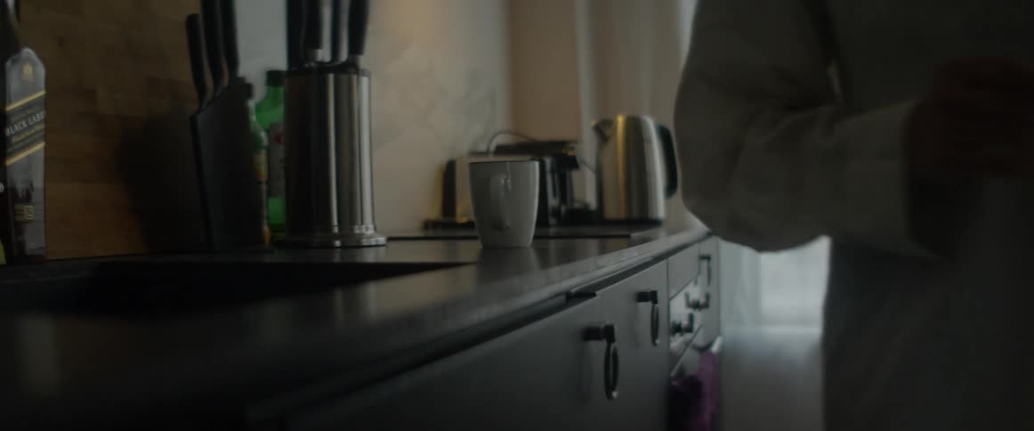 Coffee mug is placed on a countertop as cars travel outside the window