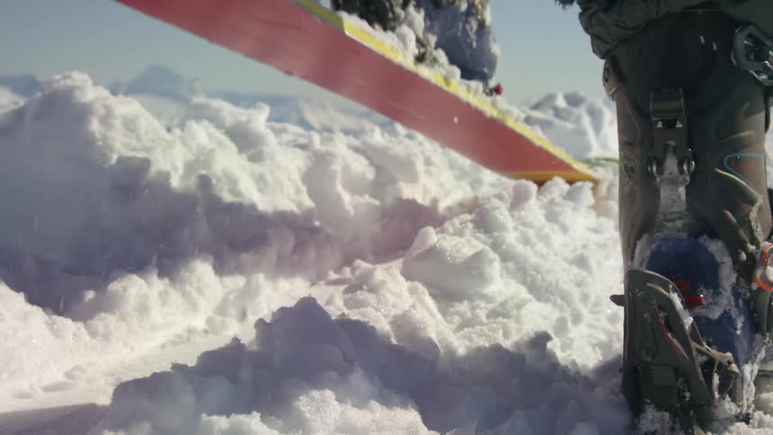 A skier tries to shake snow off by stomping on the ground