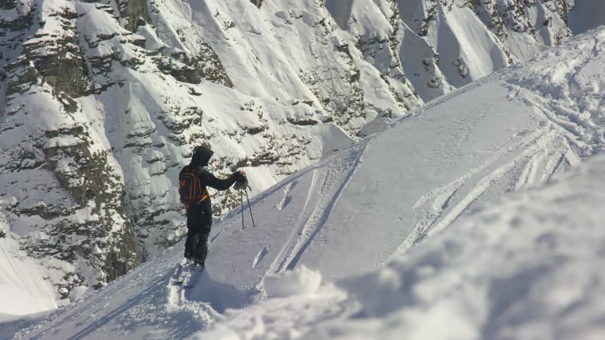 A person checks ski gear standing on the snow covered slope of a mountain