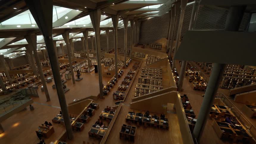 A library with many desks and units in wood with columns and skylights