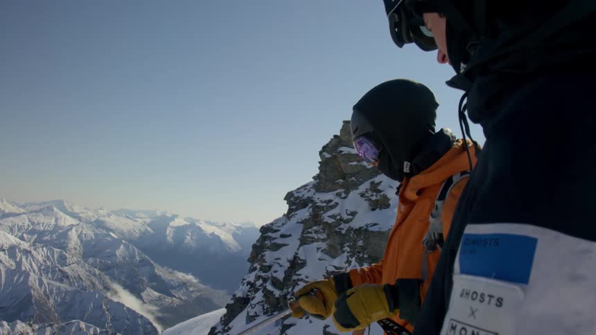 Two skiers looking down the snow covered slopes of a mountain range at day time