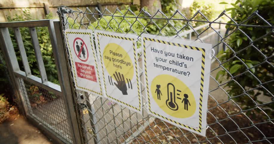 Signs hanging on a chain link fence blocking a walkway